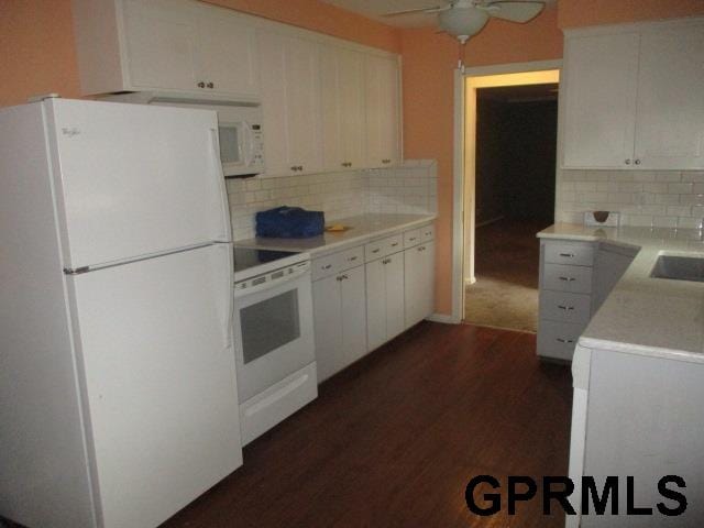 kitchen featuring white appliances, dark hardwood / wood-style flooring, tasteful backsplash, ceiling fan, and white cabinets