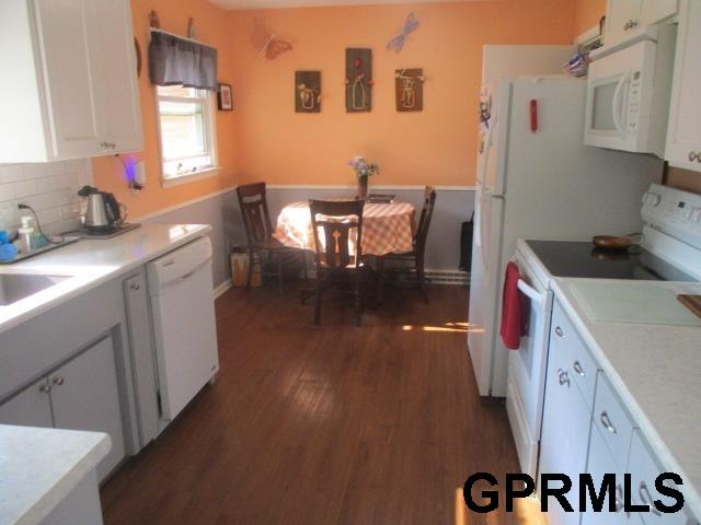 kitchen featuring backsplash, white cabinetry, white appliances, and dark hardwood / wood-style floors