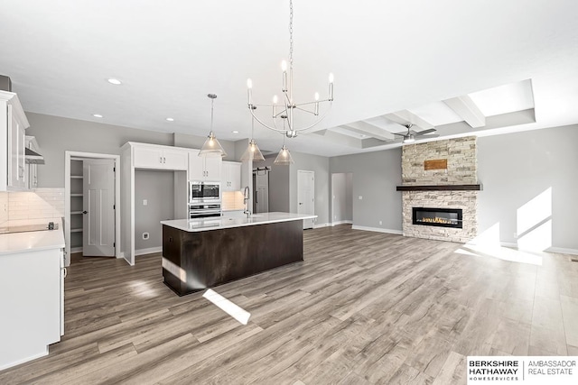 kitchen featuring hanging light fixtures, tasteful backsplash, a kitchen island with sink, white cabinetry, and stainless steel appliances