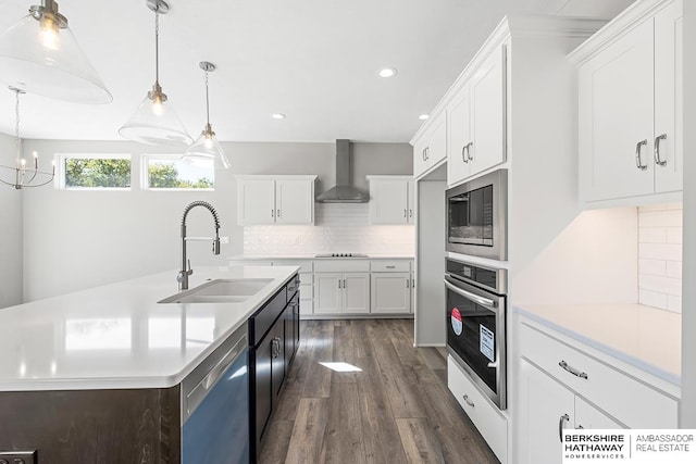 kitchen featuring dark hardwood / wood-style floors, sink, white cabinetry, wall chimney range hood, and appliances with stainless steel finishes