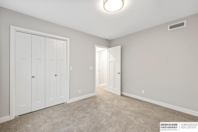 unfurnished bedroom with carpet, a closet, and a textured ceiling