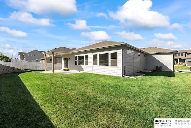 rear view of property featuring a lawn, central AC, and a patio area