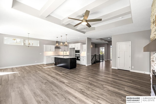 unfurnished living room featuring ceiling fan with notable chandelier, sink, and dark hardwood / wood-style flooring