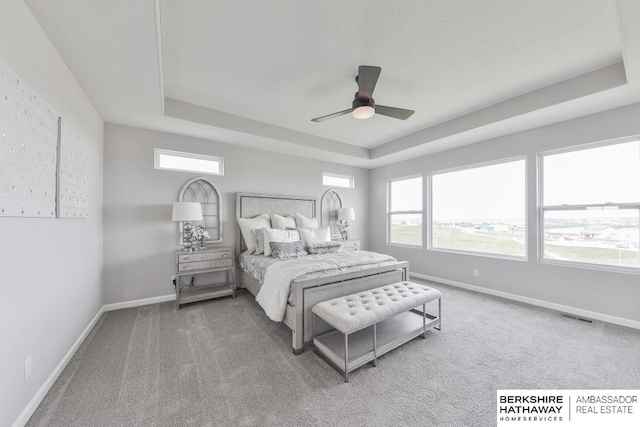 bedroom with ceiling fan, a tray ceiling, and carpet flooring