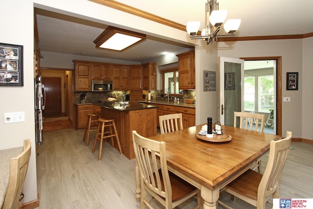 dining space with ornamental molding, light hardwood / wood-style flooring, and an inviting chandelier