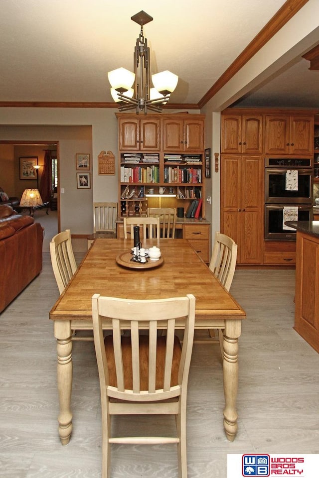 dining room featuring an inviting chandelier, light hardwood / wood-style floors, and crown molding