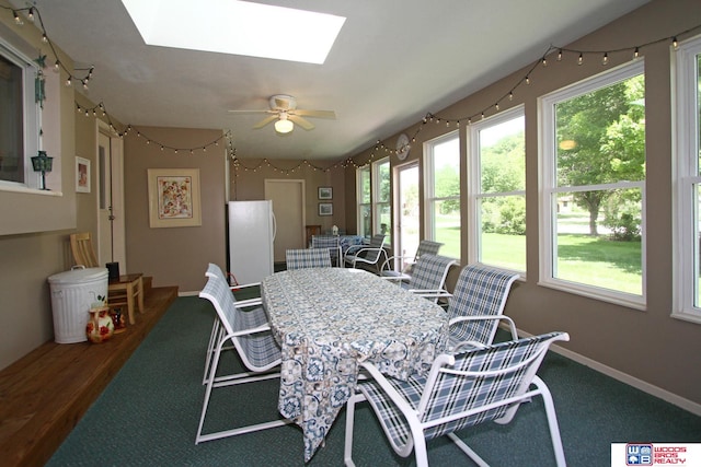 dining room with a skylight, ceiling fan, a wealth of natural light, and wood-type flooring