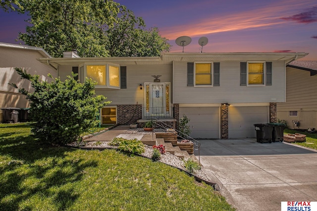 bi-level home featuring a garage and a yard