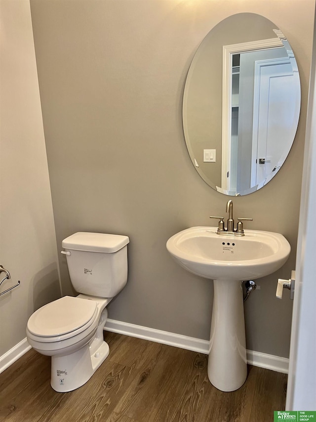 bathroom with wood finished floors, baseboards, and toilet