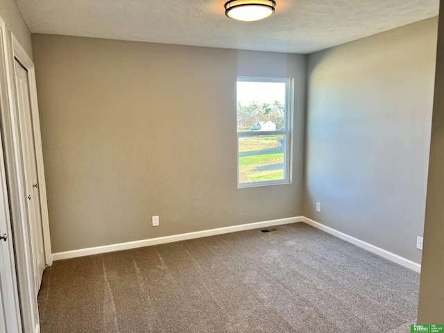 unfurnished bedroom featuring dark colored carpet, baseboards, and a closet