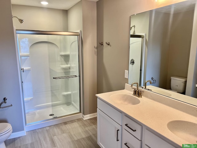 bathroom with toilet, baseboards, a shower stall, and double vanity
