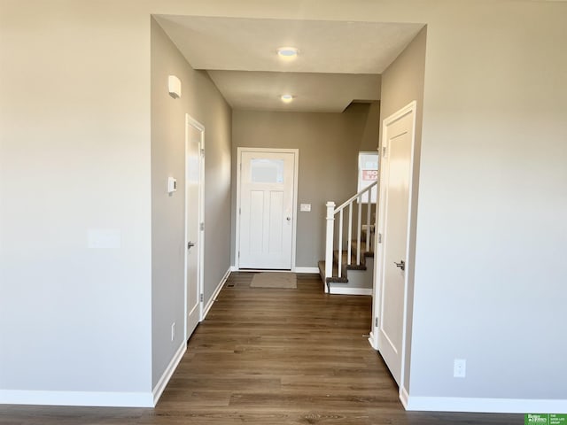 doorway with baseboards, dark wood-type flooring, and stairs