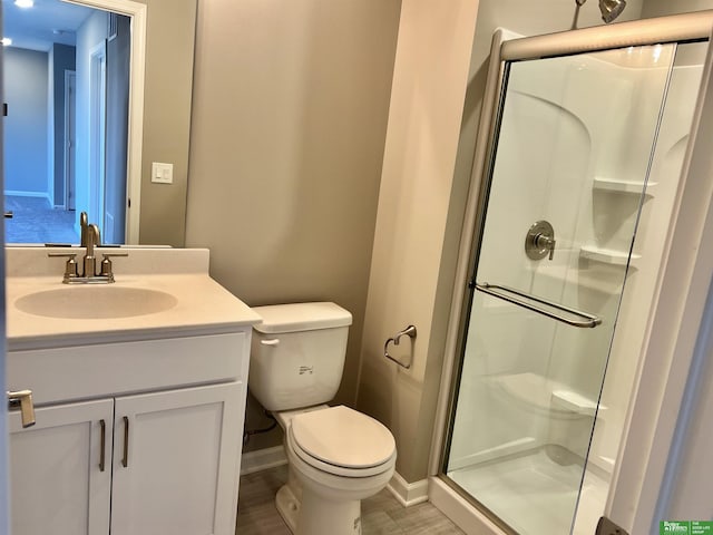 full bathroom with a shower stall, toilet, baseboards, and vanity