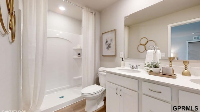 bathroom featuring a shower with shower curtain, hardwood / wood-style floors, vanity, and toilet