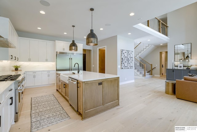 kitchen with light stone countertops, premium appliances, white cabinets, decorative light fixtures, and a large island