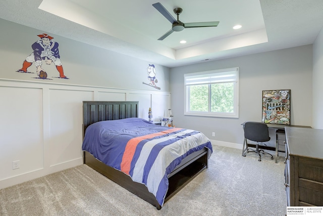 bedroom with ceiling fan, carpet, and a tray ceiling