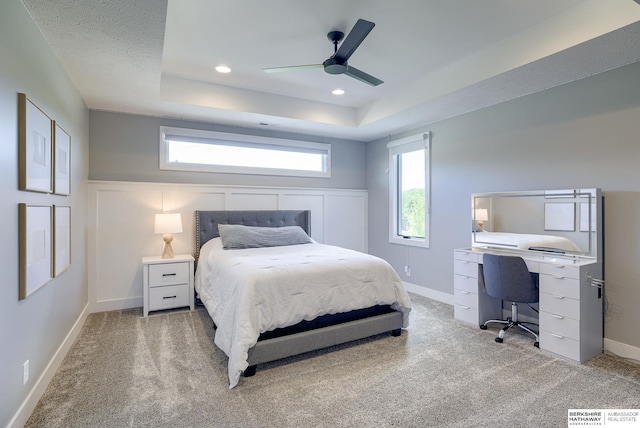 bedroom with ceiling fan, a textured ceiling, a tray ceiling, and carpet floors