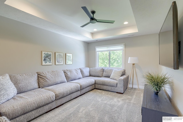 carpeted living room featuring ceiling fan and a raised ceiling