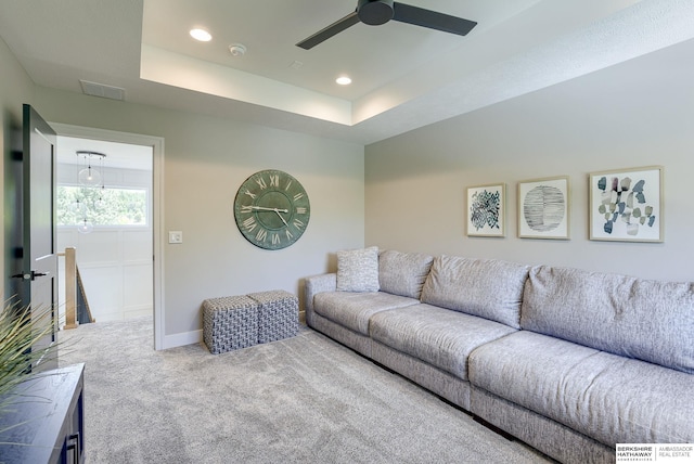 carpeted living room with ceiling fan and a tray ceiling