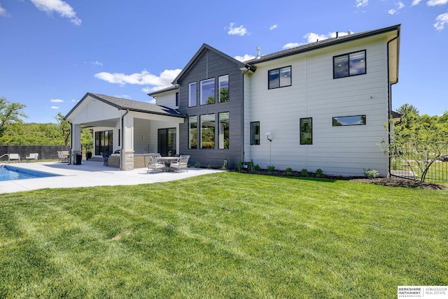 rear view of house with a patio area, a fenced in pool, and a lawn