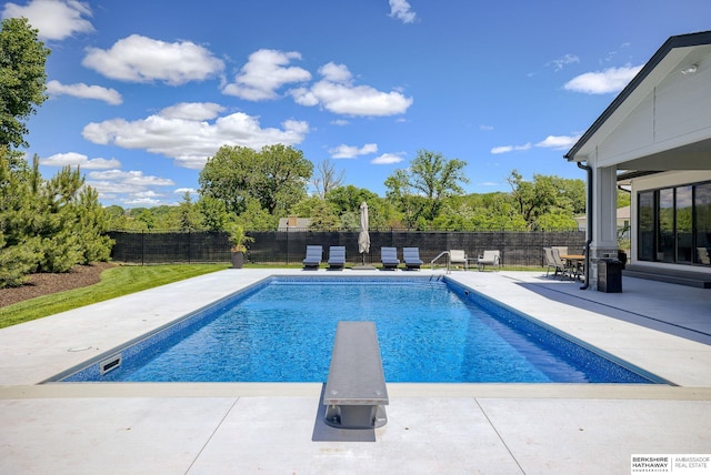 view of swimming pool featuring a diving board and a patio