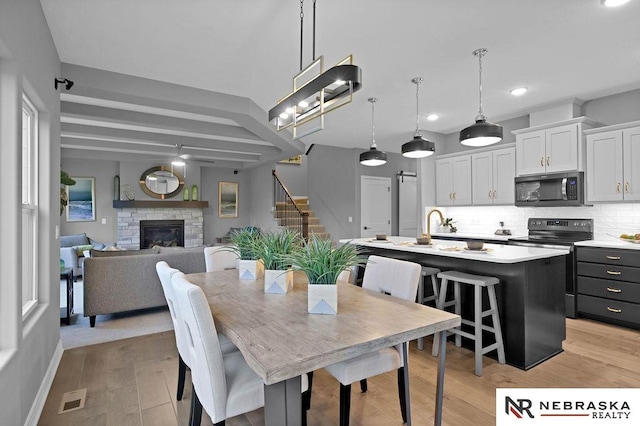 dining room featuring a stone fireplace and light wood-type flooring