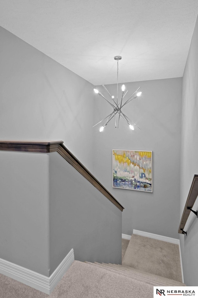 stairs with a chandelier and carpet floors