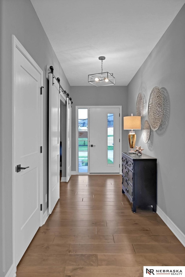 foyer featuring an inviting chandelier, dark hardwood / wood-style flooring, and a barn door