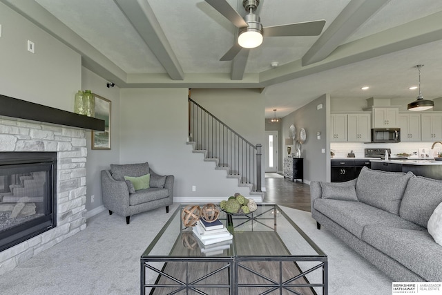 living room with beam ceiling, ceiling fan, and a fireplace