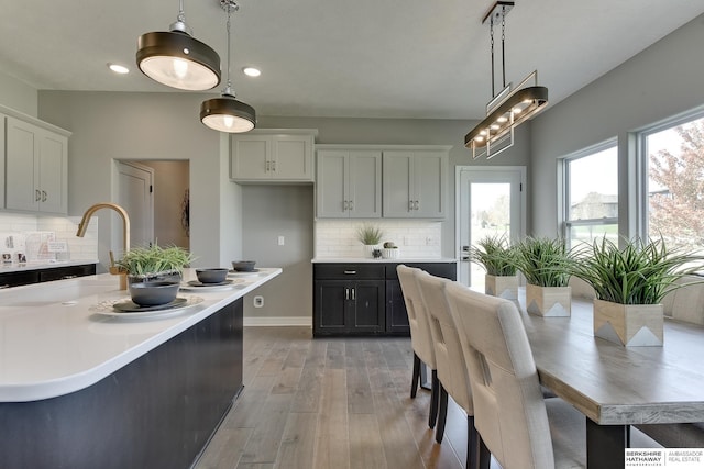 kitchen featuring white cabinets, pendant lighting, light wood-type flooring, and decorative backsplash