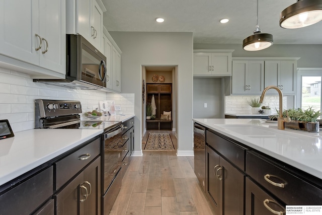 kitchen featuring white cabinetry, sink, stainless steel appliances, and decorative light fixtures