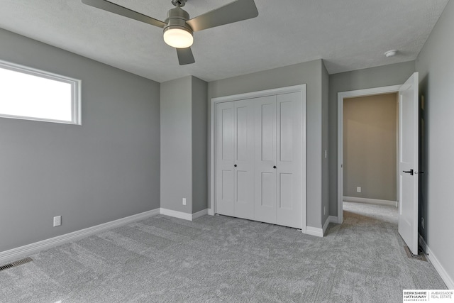 unfurnished bedroom featuring ceiling fan, light colored carpet, and a closet