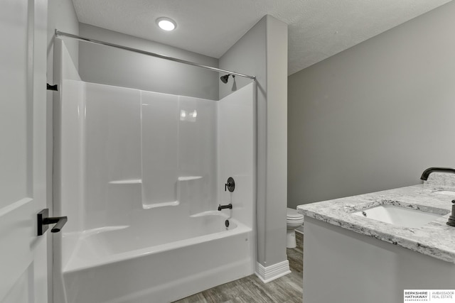 full bathroom with wood-type flooring,  shower combination, a textured ceiling, toilet, and vanity