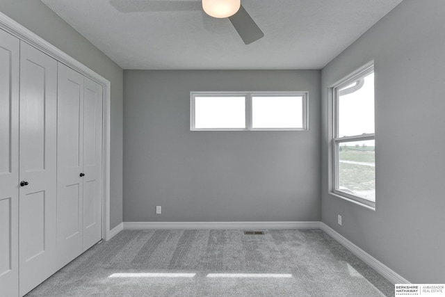 unfurnished bedroom featuring ceiling fan, light carpet, and a closet