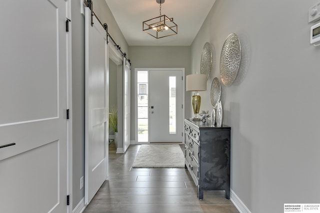 entryway with a barn door, dark hardwood / wood-style floors, and an inviting chandelier