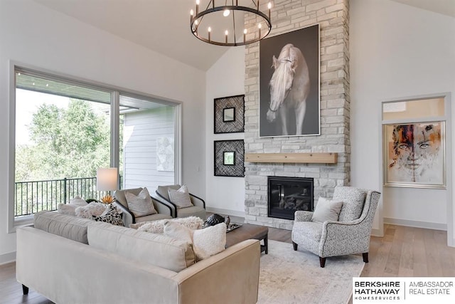 living room featuring a fireplace, high vaulted ceiling, a chandelier, and light wood-type flooring