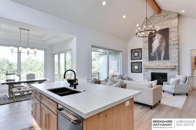 kitchen featuring a center island with sink, decorative light fixtures, sink, and light hardwood / wood-style flooring