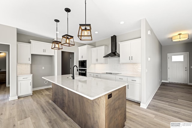 kitchen with tasteful backsplash, white cabinetry, a kitchen island with sink, and wall chimney range hood