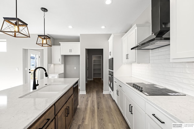 kitchen featuring pendant lighting, white cabinets, sink, wall chimney exhaust hood, and light stone countertops