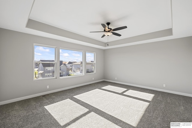 carpeted spare room featuring a raised ceiling and ceiling fan