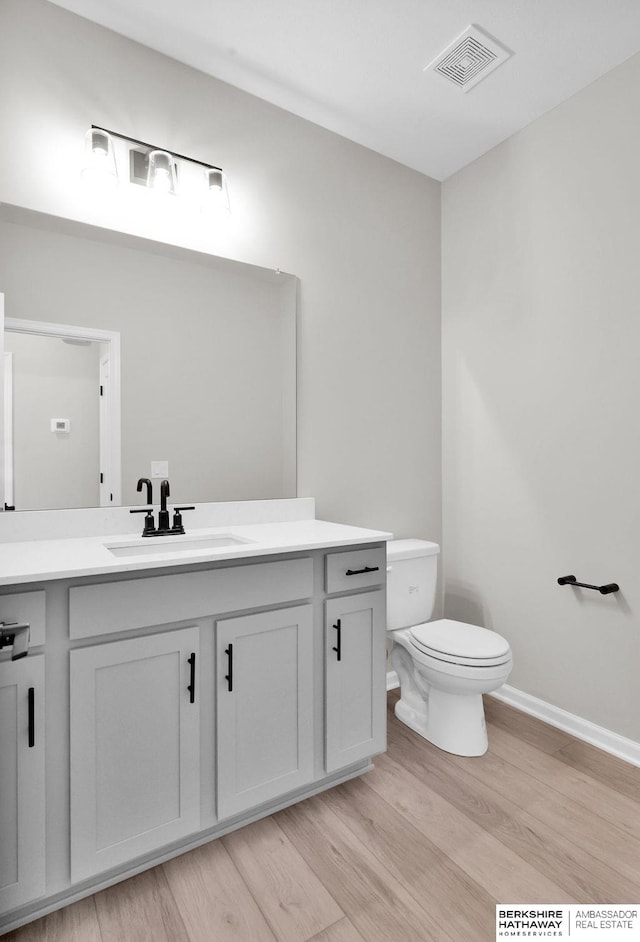 bathroom featuring vanity, wood-type flooring, and toilet