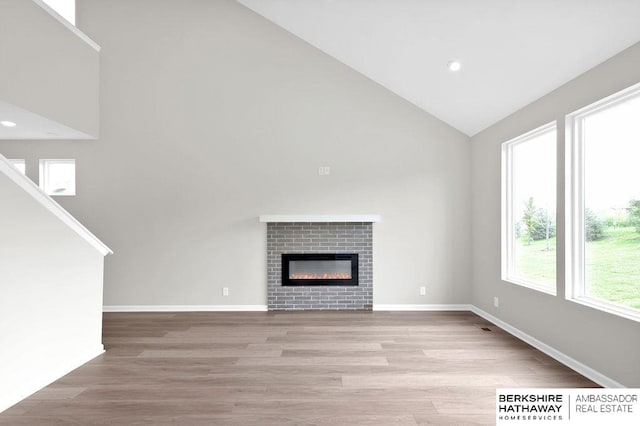 unfurnished living room with high vaulted ceiling and light wood-type flooring