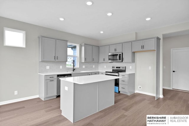 kitchen with gray cabinetry, tasteful backsplash, stainless steel appliances, and a kitchen island