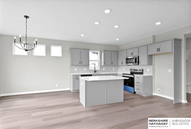 kitchen featuring gray cabinets, appliances with stainless steel finishes, a center island, and sink