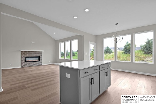 kitchen featuring pendant lighting, a fireplace, light hardwood / wood-style floors, and a kitchen island