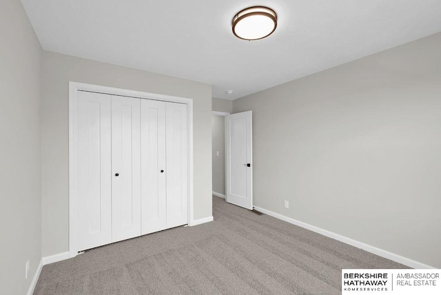 unfurnished bedroom featuring light colored carpet and a closet