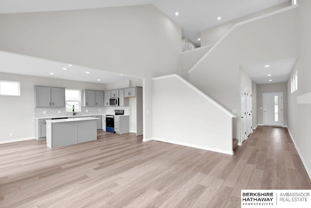 unfurnished living room featuring light hardwood / wood-style flooring and high vaulted ceiling