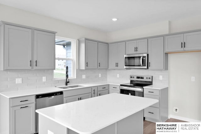 kitchen with tasteful backsplash, sink, stainless steel appliances, and a center island