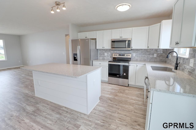 kitchen with light stone countertops, appliances with stainless steel finishes, a center island, and white cabinets