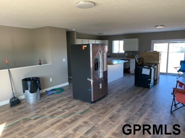 kitchen featuring a kitchen island, white cabinetry, hardwood / wood-style flooring, stainless steel refrigerator with ice dispenser, and electric stove